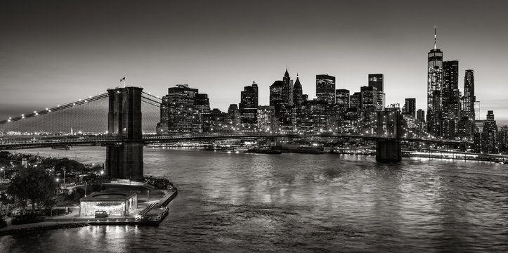 Black & White elevated view of the Brooklyn Bridge and Lower Manhattan skyscrapers at dusk. Skyline of the Financial District with East River. New York City