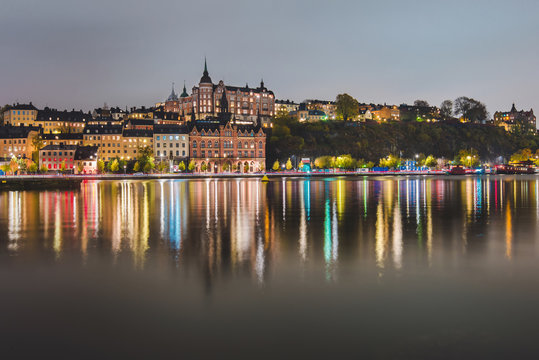 Stockholm city lights and night view of Sodermalm district buildings reflected in the water. Evening Stockholm cityscape with illumination, Riddarfjarden marina and Soder Malarstrand embankment.