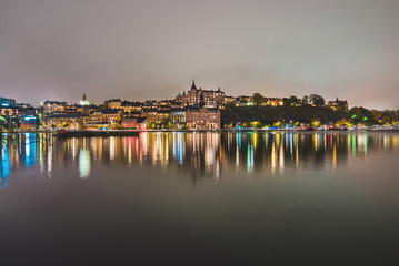Stockholm city lights and night view of Sodermalm district buildings reflected in the water. Evening Stockholm cityscape with illumination, Riddarfjarden marina and Soder Malarstrand embankment.