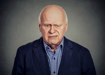 Obraz premium Elderly sad skeptical man looking down