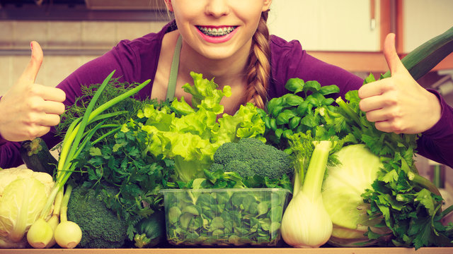 Woman in kitchen with green vegetables