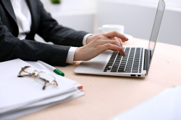 Close up of business woman  hands  typing on  laptop computer in the white colored office.