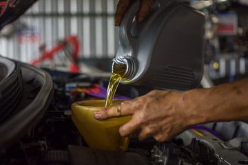 Car mechanic fills a fresh lubricant engine oil