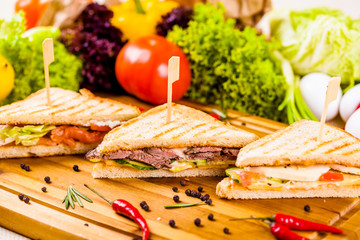 Sandwiches with different fillings on wooden board
