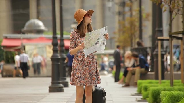 Splendid sightseer girl looks at a map, and asks a passerby girl for directions