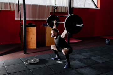 Fototapeta na wymiar Fit young athlete lifting the barbell in gym. Gym training