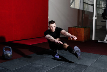 Muscular bearded man doing pistol squats on one leg in gym