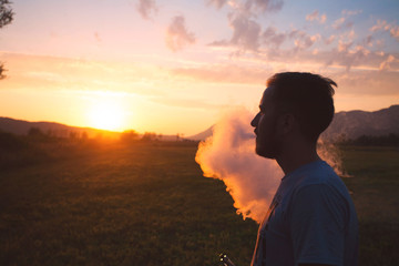 Man with beard smoke electronic cigarette outdoor. Smoke of electronic cigarette