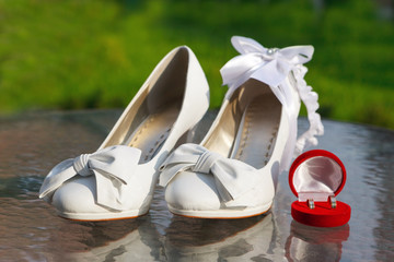 White bride's shoes, garter and wedding rings in red box