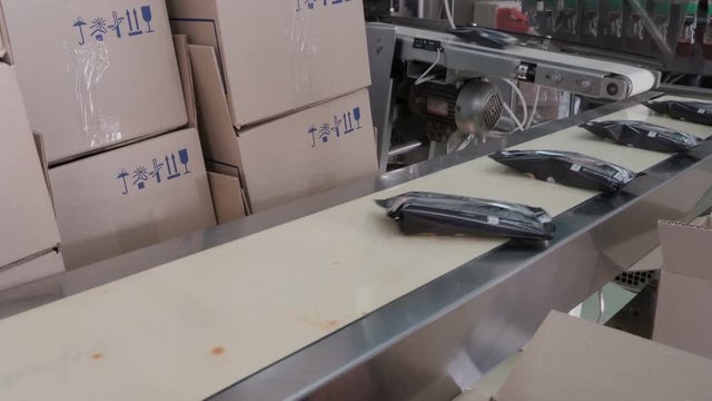 Packing of ice-cream in a wrapper. Automatic packing line of ice cream. Worker is picking ice cream in a box.