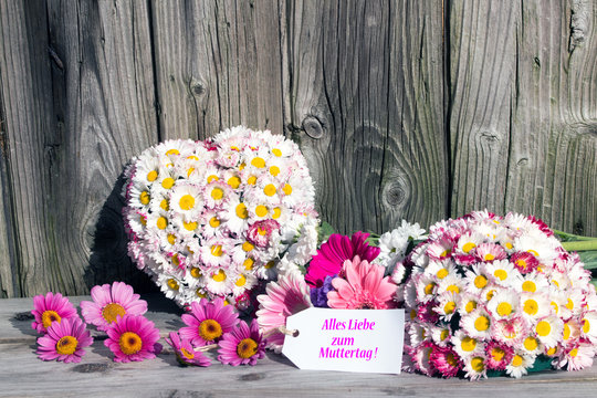 Herz aus Gänseblümchen und Text  "Alles Liebe zum Muttertag" rustikal vor Holzhintergrund