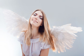An angel from heaven. Young, wonderful blonde girl in the image of an angel with white wings.
