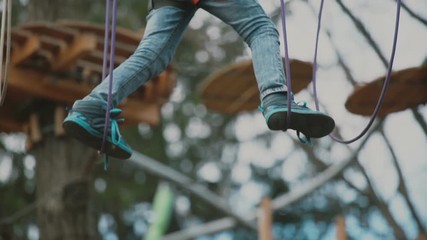 young boy passing the cable route high among trees, extreme sport in adventure park