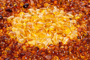 Stones of yellow and dark yellow amber lie on a flat surface.
