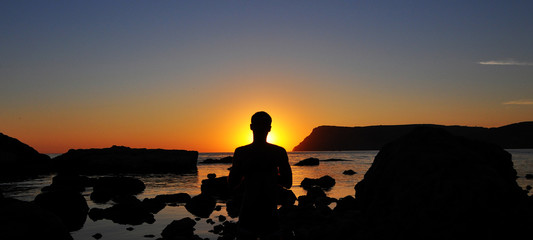 Silhouette man that meditating at sunset