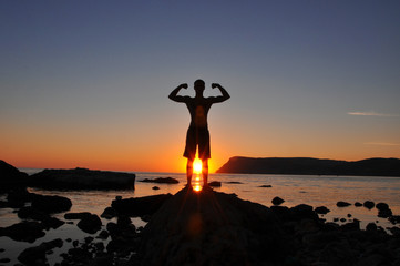 trained male body silhouette on the beach at sunset