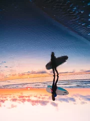 Sportliches Surfmädchen geht zum Surfen auf Ozean. Frau im Neoprenanzug, Silhouette bei Sonnenuntergang © artifirsov