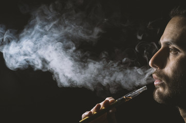 Young man holding and vaping an electronic cigarette, e-cig, ecigarette.
