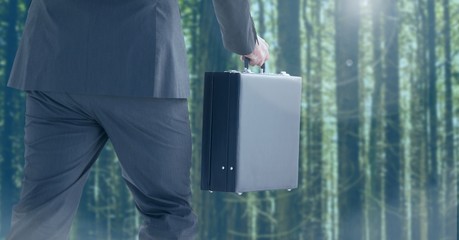 Businessman legs walking in forest with briefcase