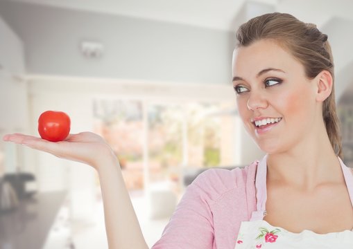 Cook woman in the kitchen of the house looking the tomato