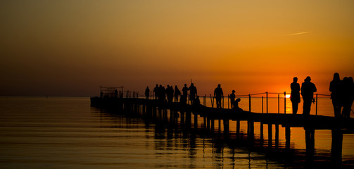 Sea sunset. Silhouettes of people on the sea pier