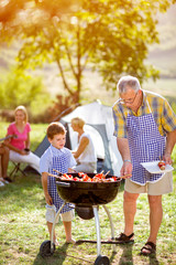 grandfather and grandson making barbecue .