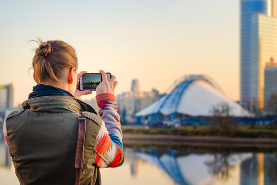 Young woman takes pictures of the city on a smartphone