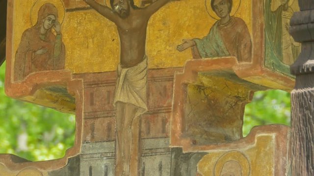 Tilt shot to an orthodox ancient outdoor painted crucifix.