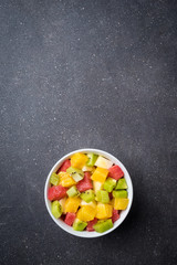 Colorful fruit salad on gray stone table. Food background