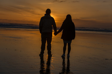 couple holding hands at beach at sunset