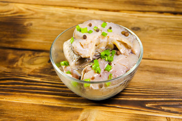 Marinated carp in glass bowl on wooden table