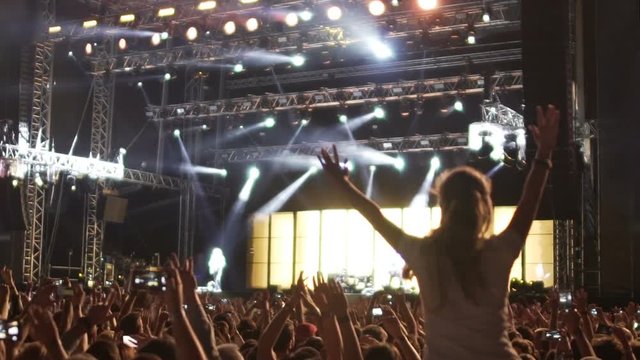 Crowd of devoted fans jumping and dancing at rock concert, super slow motion