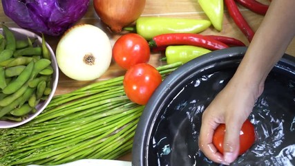 Woman washing raw fresh vegetables.
