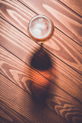 Overhead shot of beer glass on wooden table. Close up