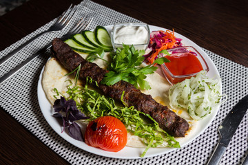 Kebab on pita bread with vegetables, onions and sauce.