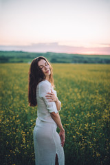 Fototapeta na wymiar Girl walking in the field at sunset