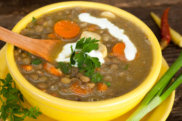 Hot soup with green lentil, vegetables and spices in clay bowl