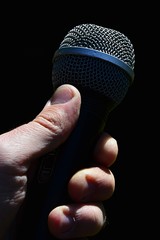 Dynamic professional vocal microphone held in adult male left hand