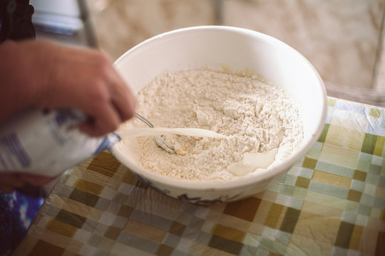 Grandmother Pouring Milk Into Pancake Batter