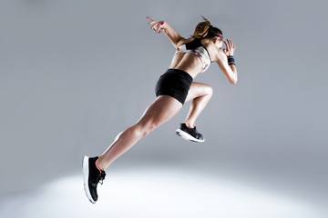 Fit and sporty young woman running on white background.