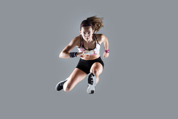 Fit and sporty young woman jumping on white background.