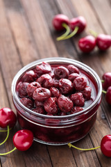Berries cherry with syrup in a glass jar. Canned fruit