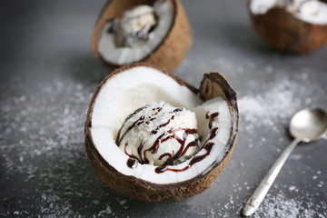 Ice cream with desiccated coconut and chocolate syrup in half of nut on grunge background