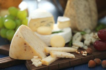 Wooden board with variety of cheese on table