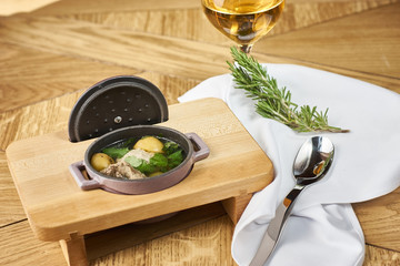 Potato soup with meatballs served on wooden table with spoon and glass of wine