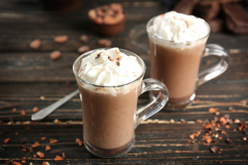 Glass cups of cocoa with whipped cream on wooden table