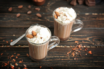 Glass cups of cocoa with whipped cream on wooden table