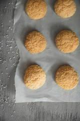 Delicious coconut cookies covered with flakes on parchment paper