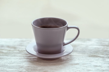 Cup of hot tea on wooden table against blurred background