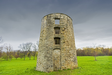 Fototapeta na wymiar Rustic old brick silo ruin stands tall against a stormy blue sky